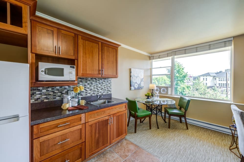 A cozy kitchen and dining area with wooden cabinets, a small round table, and a window providing natural light.
