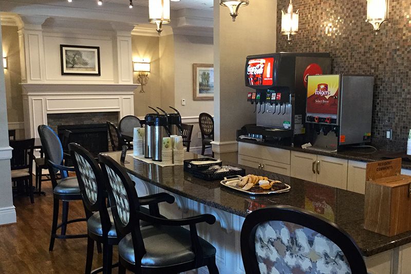 A cozy lounge area with a coffee and beverage station, featuring comfortable seating and snacks on the counter.