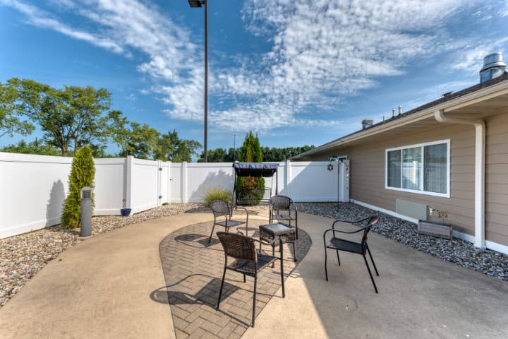 An outdoor patio area with chairs and a table under a clear sky.