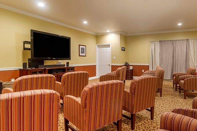 A cozy home theater room with several striped chairs facing a large television screen.