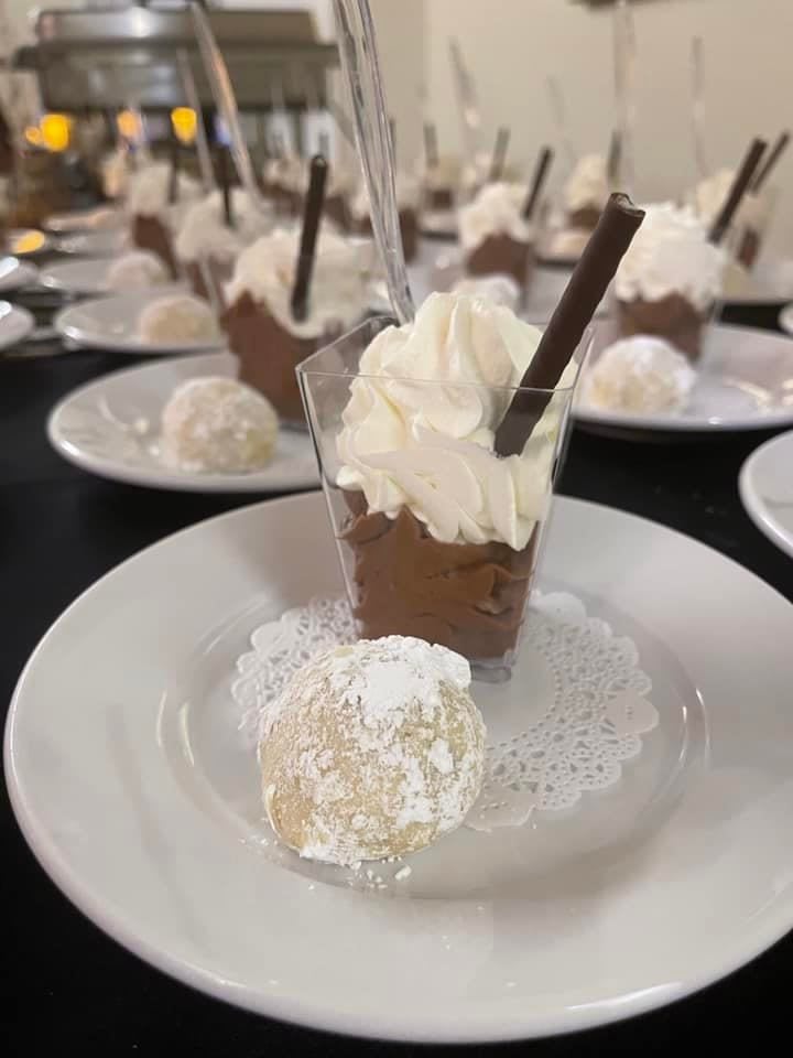 Delicious chocolate mousse topped with whipped cream and served alongside a delicate pastry.
