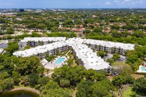 Aerial view of a residential apartment complex featuring a central swimming pool surrounded by greenery.