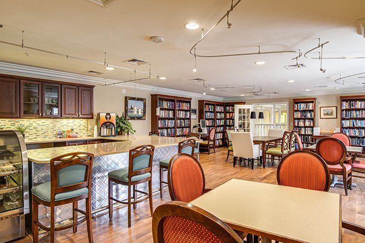 A cozy library setting with bookshelves, tables, and chairs, creating an inviting reading area.