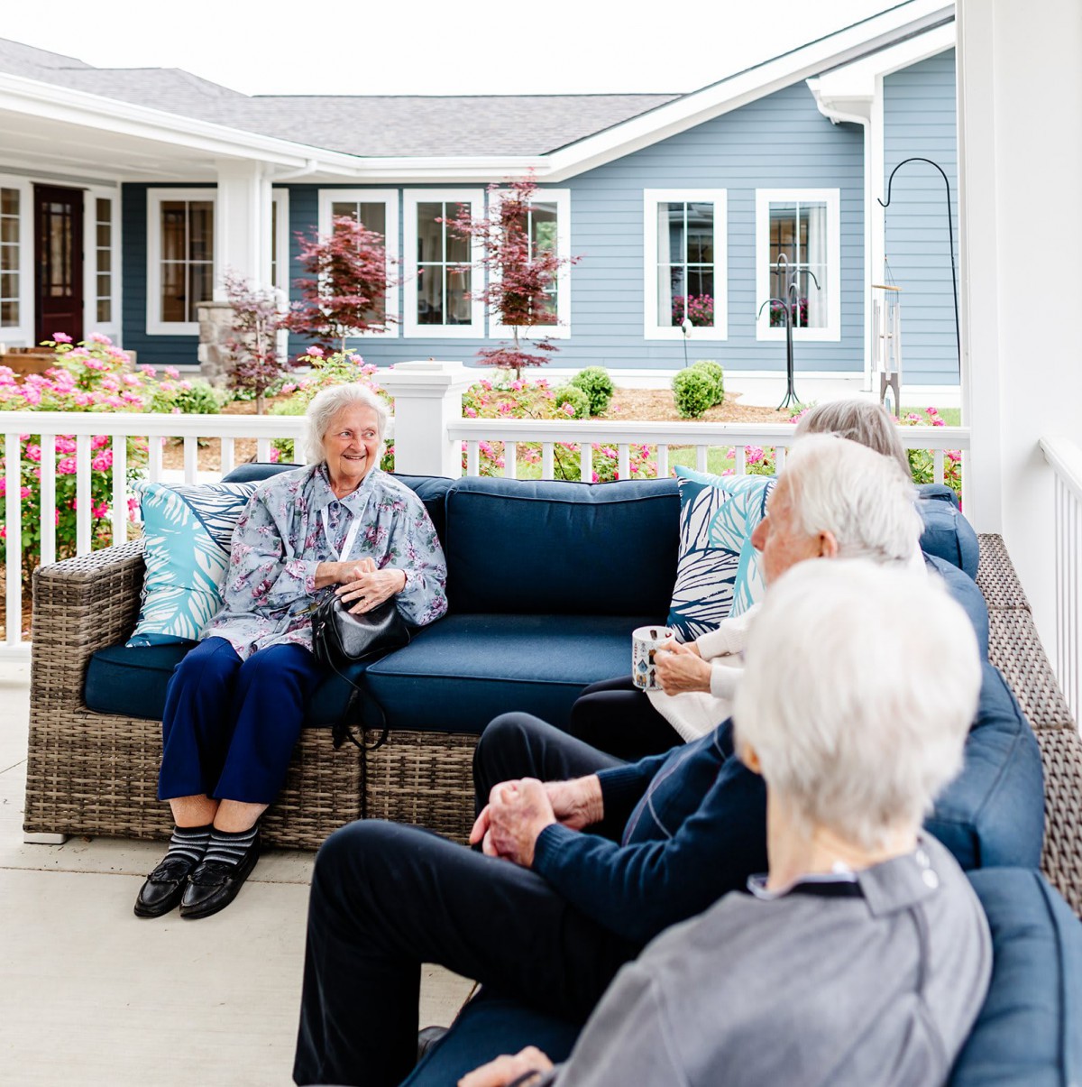 A group of seniors enjoying a conversation on outdoor couches in a community setting.