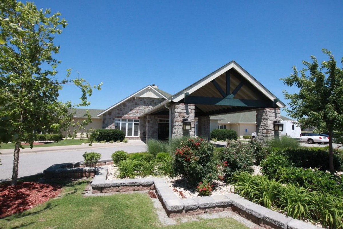 A well-maintained residential house with landscaped garden and clear blue skies.
