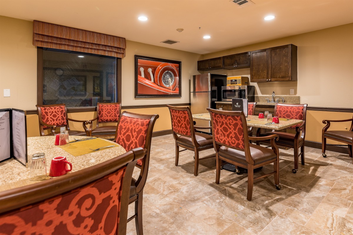 A well-decorated dining area with an open kitchen, featuring elegant furniture and artwork on the wall.