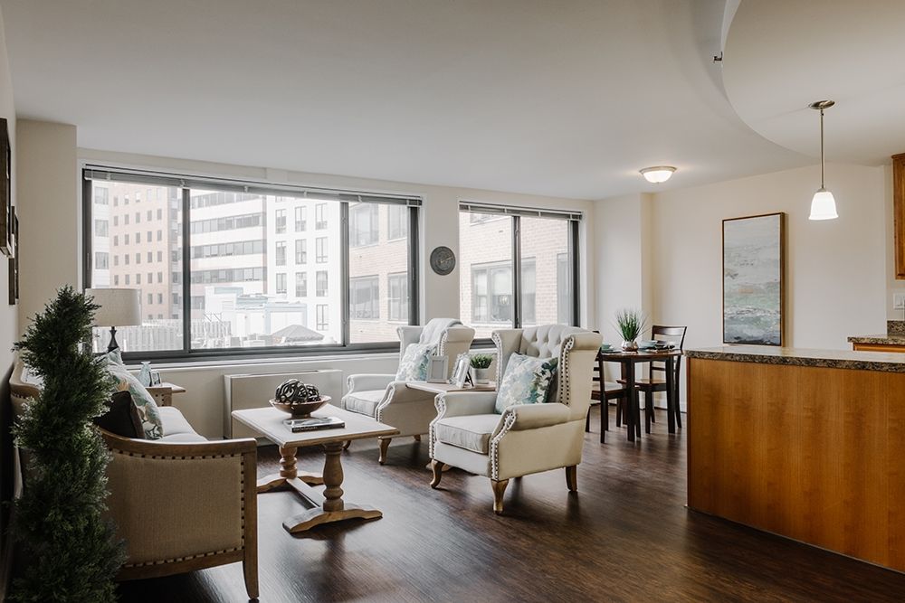 A modern apartment living room with large windows and city views.