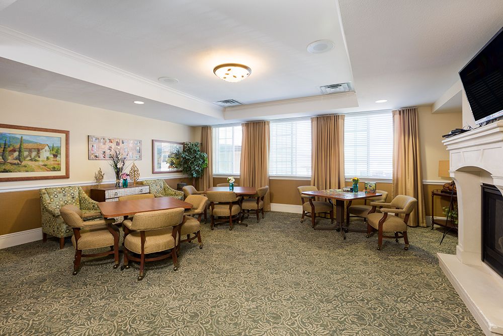 A well-furnished dining area with multiple tables and chairs, decorated with plants and artworks on the walls.