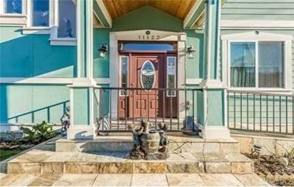 A house entrance with a wooden door, statues, and stone steps.