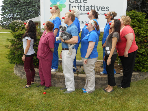 A joyful group of healthcare workers showcasing their team spirit with clown noses in front of a Care Initiatives sign.