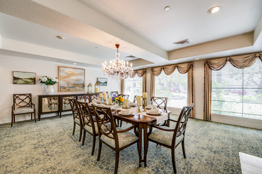 An elegant dining room featuring a wooden table, upholstered chairs, and a stunning chandelier.