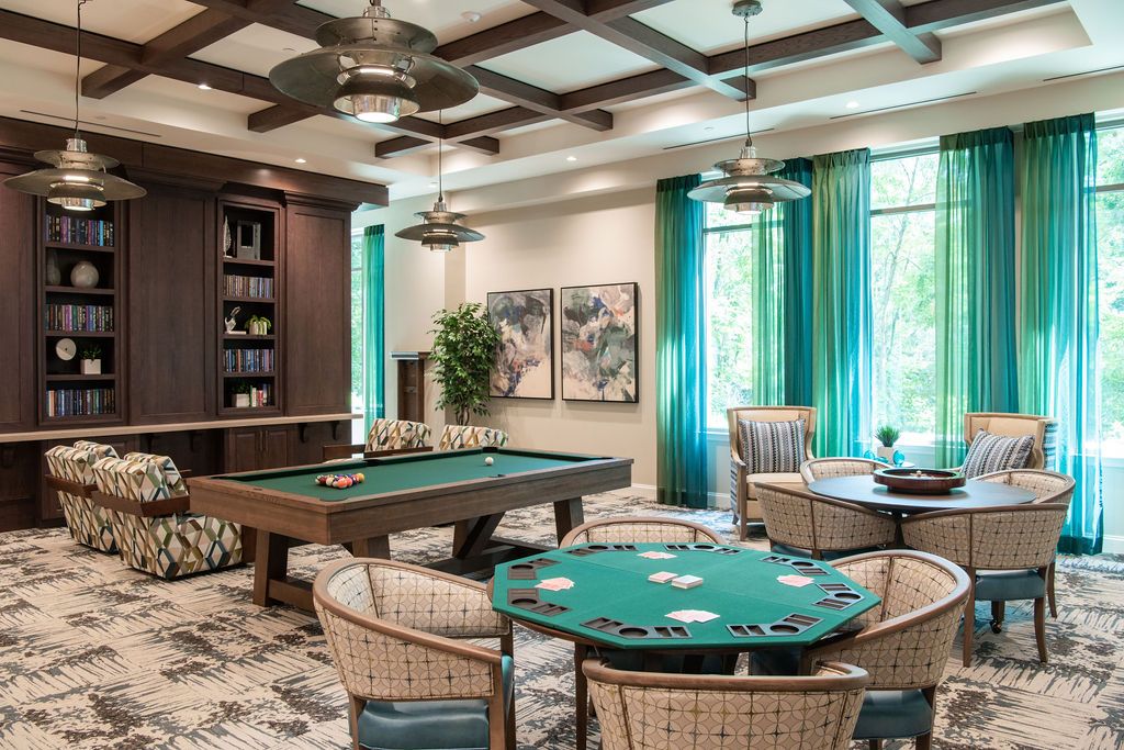 A stylish game room featuring a poker table and a billiards table, with modern decor and ambient lighting.