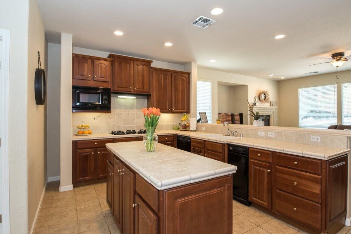 A modern kitchen with wooden cabinets and a central island, featuring sleek appliances and spacious countertops.