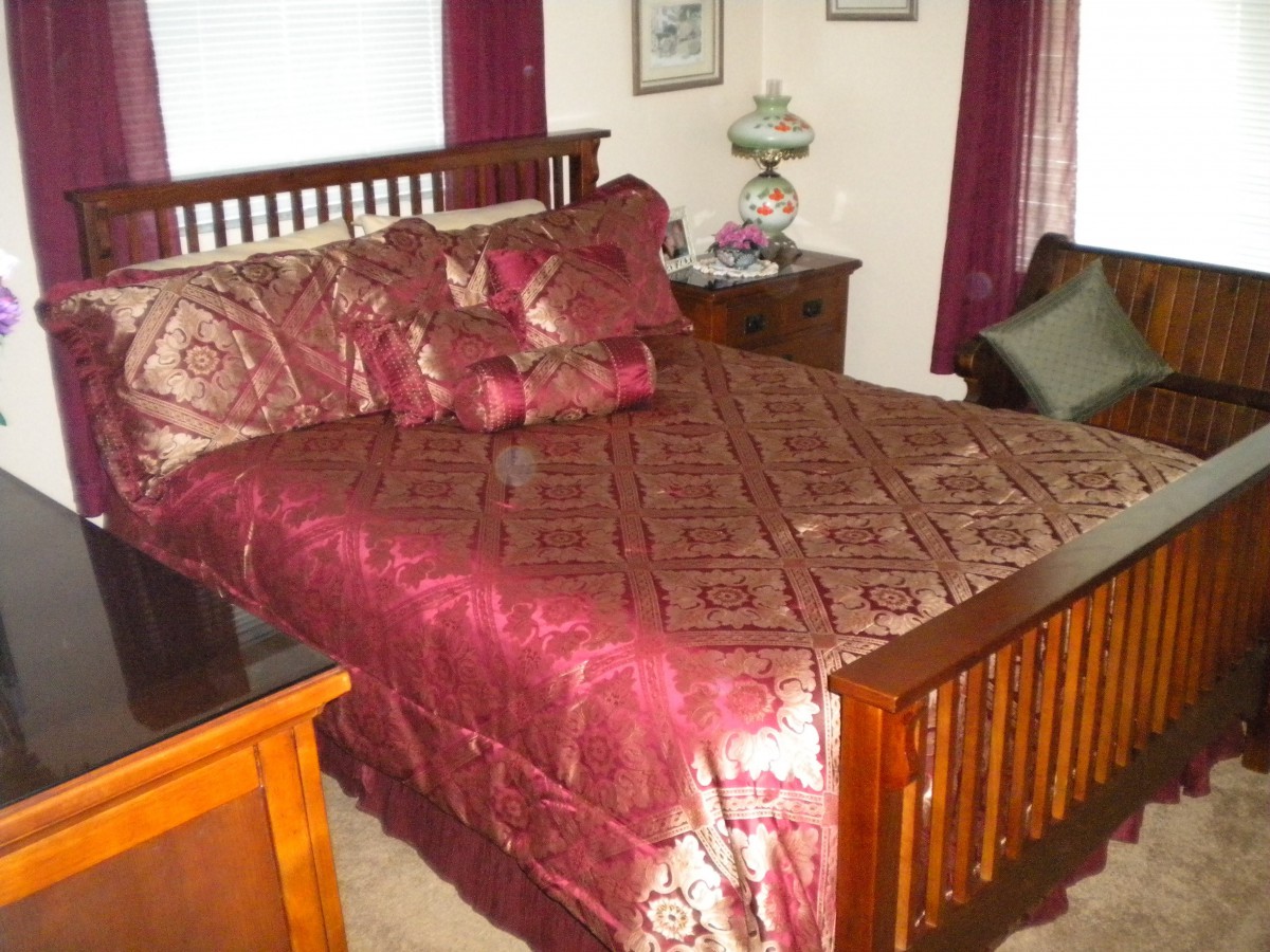 A cozy bedroom with a wooden bed frame and rich burgundy bedding.