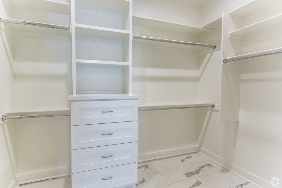 An empty white closet featuring shelves, drawers, and hanging rods for organization.