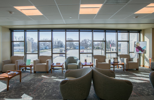 A spacious waiting room filled with comfortable chairs, illuminated by natural light streaming through large windows.