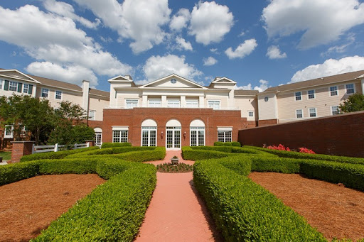 A beautiful architectural building surrounded by meticulously landscaped gardens and a clear blue sky.