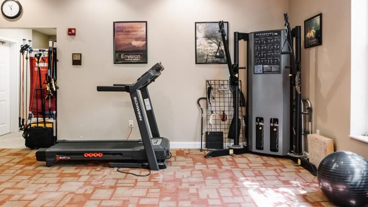 A home gym setup with a treadmill and fitness equipment on a brick floor.