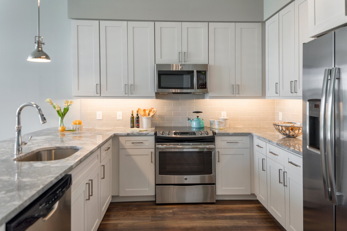 Modern kitchen with white cabinets and stainless steel appliances.