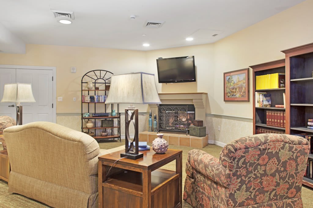 A cozy living room featuring a TV, bookshelf, and comfortable seating.