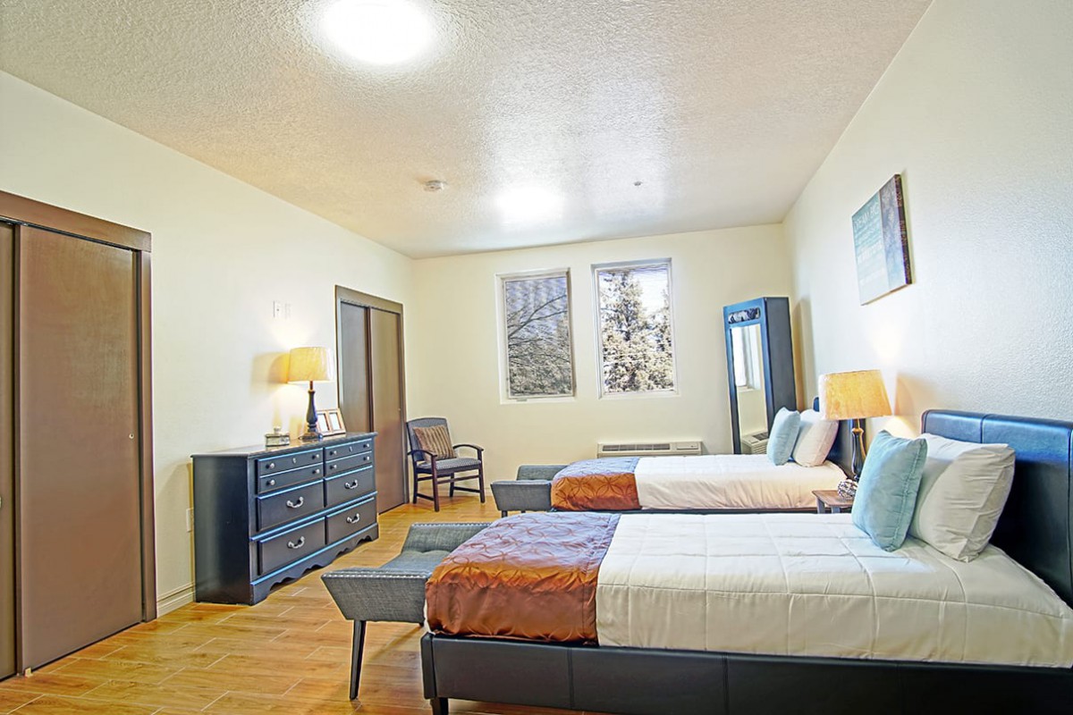 A spacious bedroom with twin beds, modern decor, and elegant furniture.