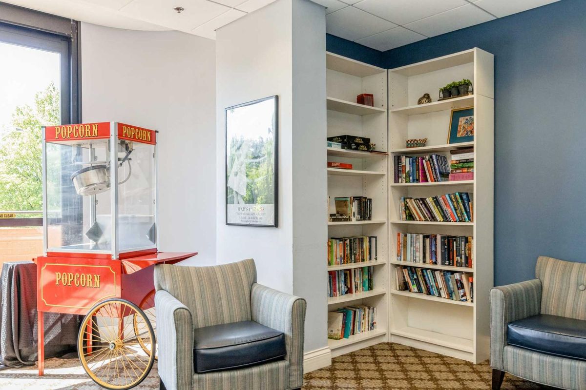 A cozy reading corner with a bookshelf and a popcorn machine.