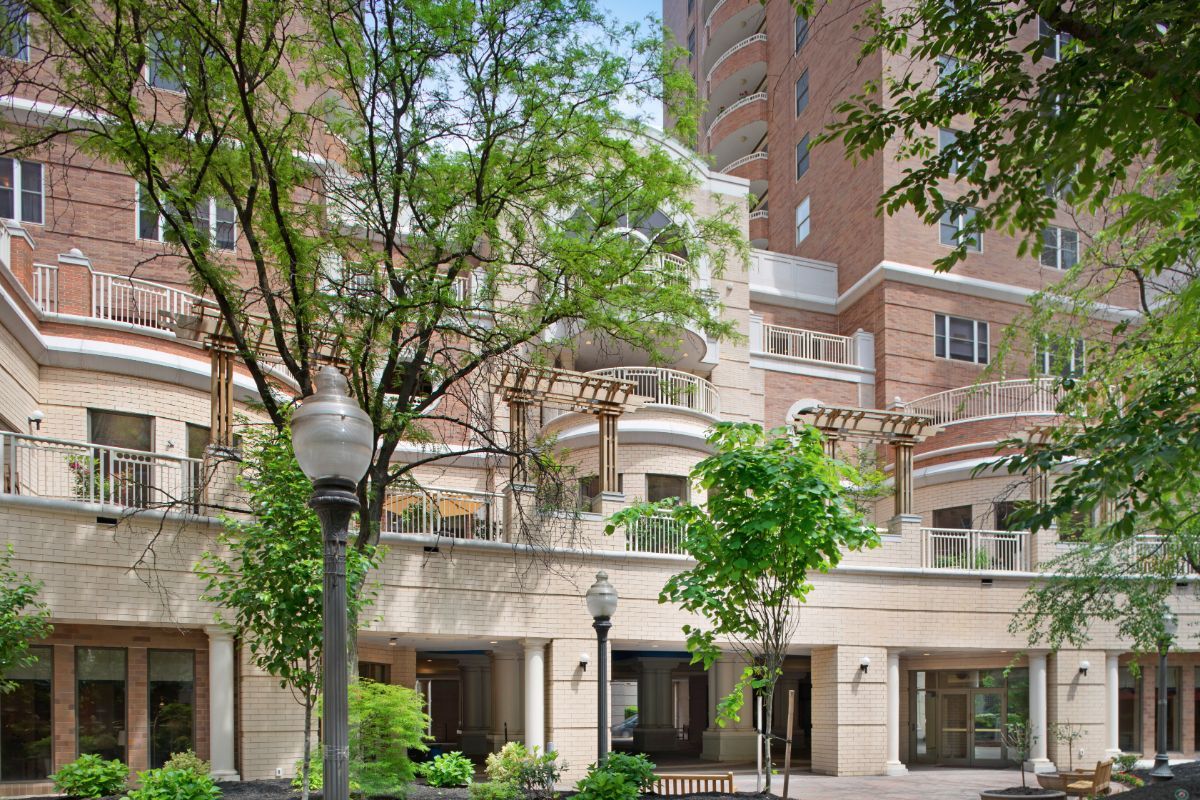 A modern residential building with surrounding trees and greenery.
