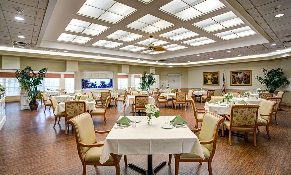 A spacious dining room with neatly arranged tables and chairs, featuring elegant decor and bright overhead lighting.