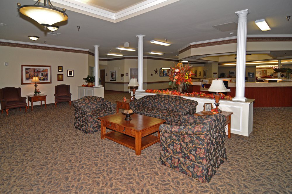 A cozy lobby area with sofas and chairs arranged around a wooden coffee table, complemented by warm lighting and decorative elements.