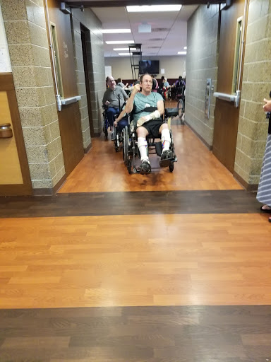 A person in a wheelchair being assisted down a hallway during an event.