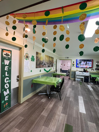 A festive dining area adorned with green decorations and a warm 'Welcome' sign.