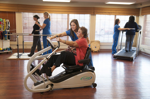 A physical therapist assists a patient using an exercise machine during a rehabilitation session.