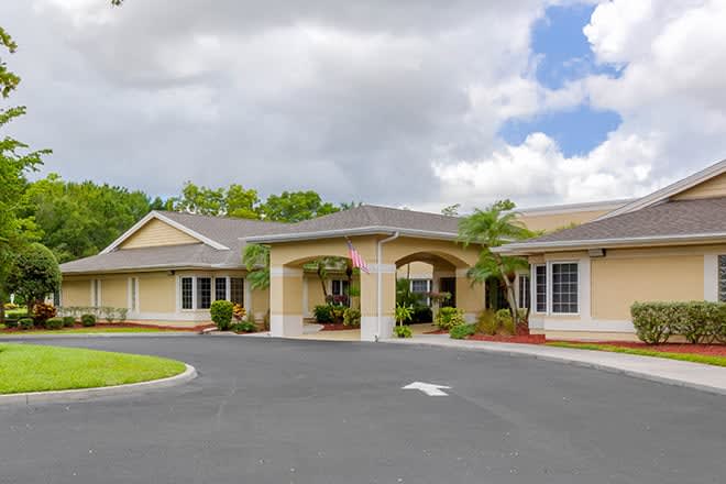 A single-story building with a large entrance and landscaped surroundings under a cloudy sky.