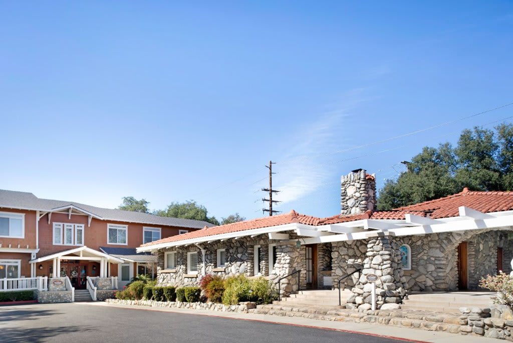 A quaint stone-walled motel under a clear blue sky.