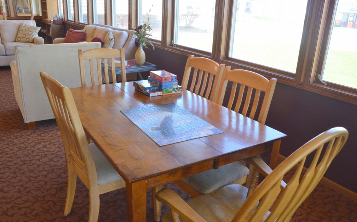 A sunlit dining area with a wooden table and chairs.