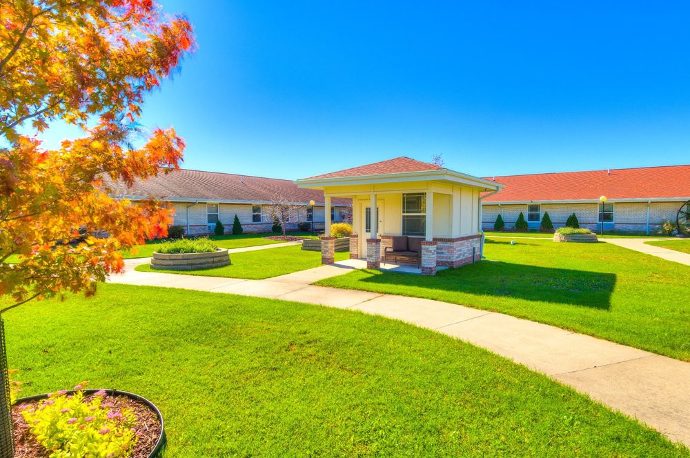 A charming cottage surrounded by a well-maintained lawn and garden on a sunny day.