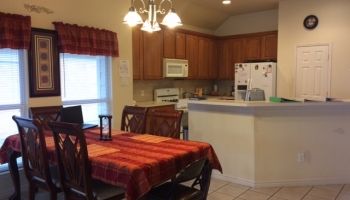 A cozy kitchen and dining area with a table set for a meal, featuring wooden cabinets and modern appliances.