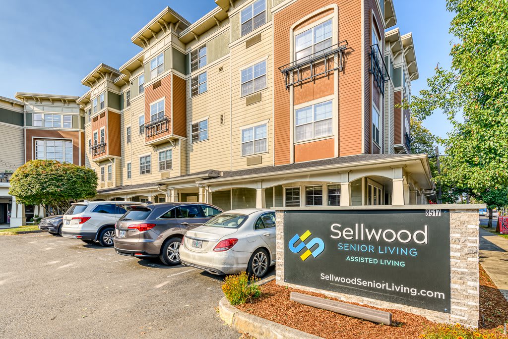 An exterior view of a senior living facility with a parking lot and visible signage.