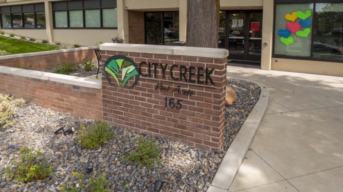 City Creek building entrance sign with landscaped surroundings.