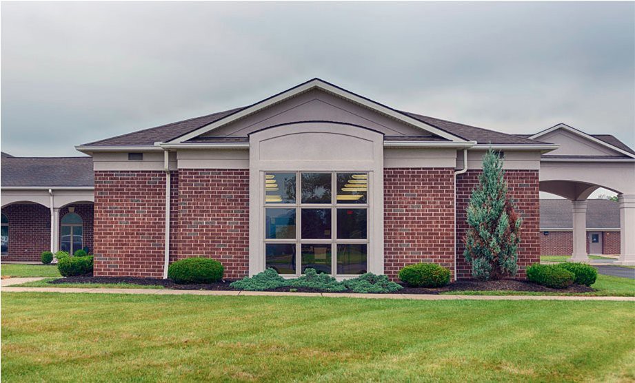 A brick building with large windows and a neatly maintained lawn.