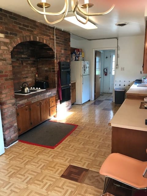 A classic kitchen with a brick wall, featuring a stove and refrigerator, complemented by a parquet floor.
