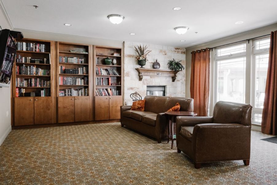 A cozy living room with bookshelves, a sofa, armchair, and fireplace.