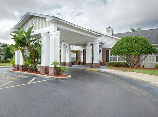 A welcoming entrance to a building with a covered driveway and lush landscaping.