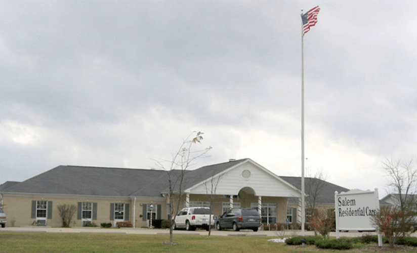 A building with a parking lot and an American flag flying on a cloudy day.