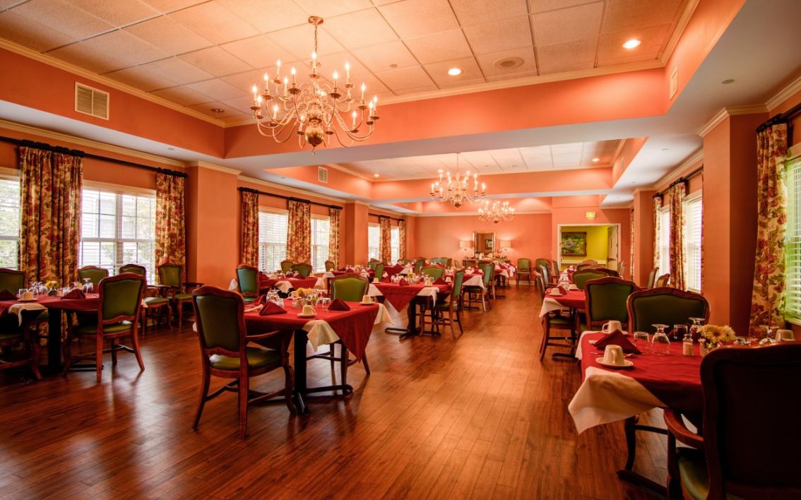 An elegant restaurant dining room with chandeliers and neatly arranged tables.