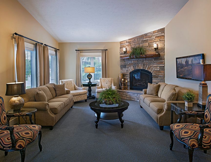 A cozy living room with elegant sofas, a central coffee table, and a brick fireplace.