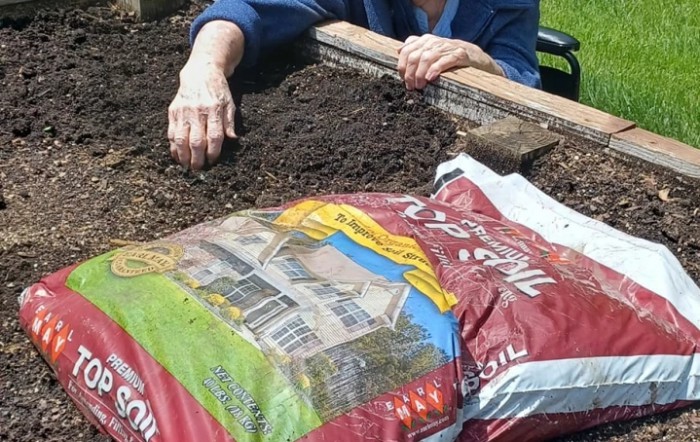 A person preparing soil in a garden bed for planting.