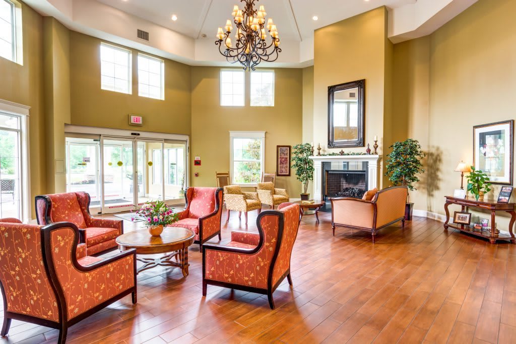 A spacious and elegantly designed living room featuring a chandelier, fireplace, and comfortable seating area.