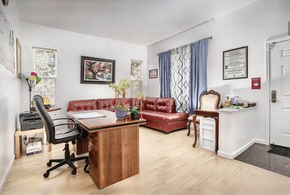 A cozy office space with a wooden desk, leather couch, and stylish decor.