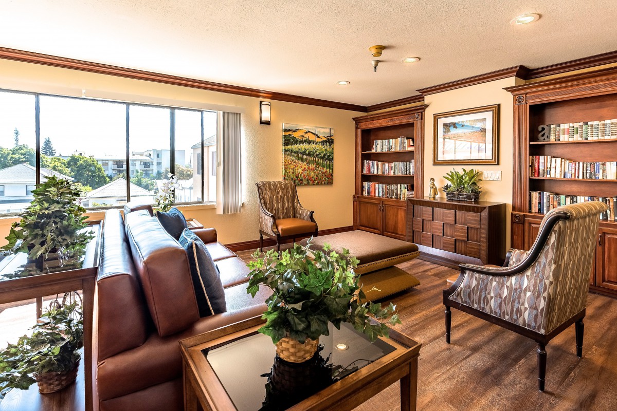 A cozy living room with modern decor, featuring a large sofa, bookshelf, and ample natural light.